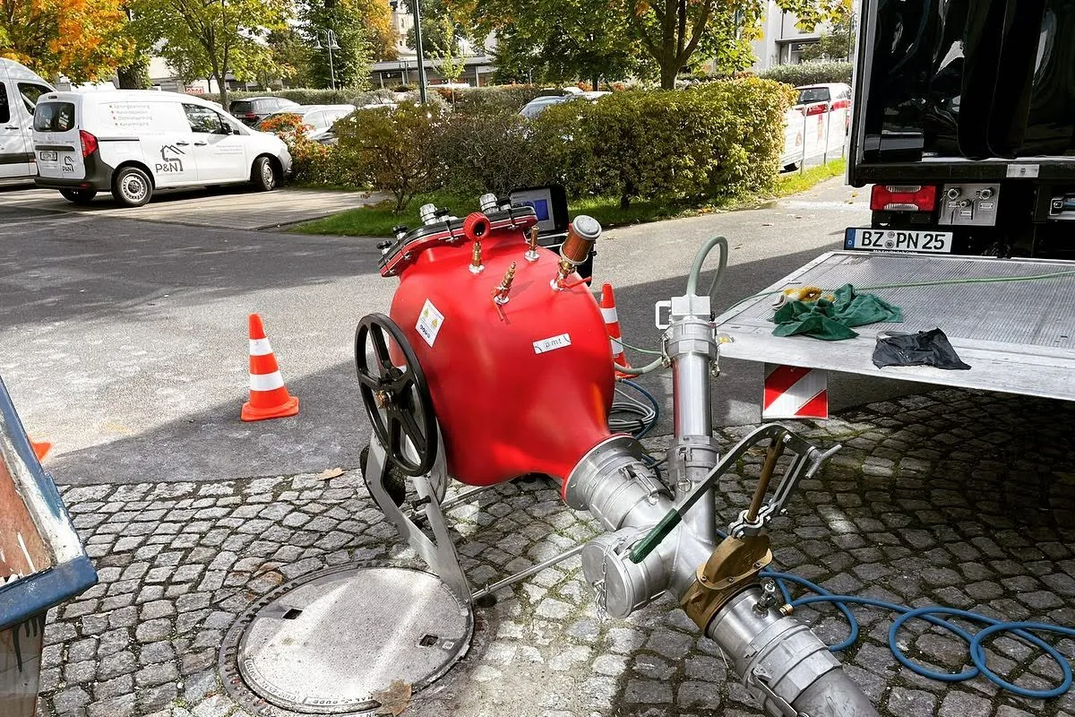 Geöffneter Schacht im Kopfsteinpflaster mit Einbautechnik des Partnerbetriebs für einen Schlauchliner